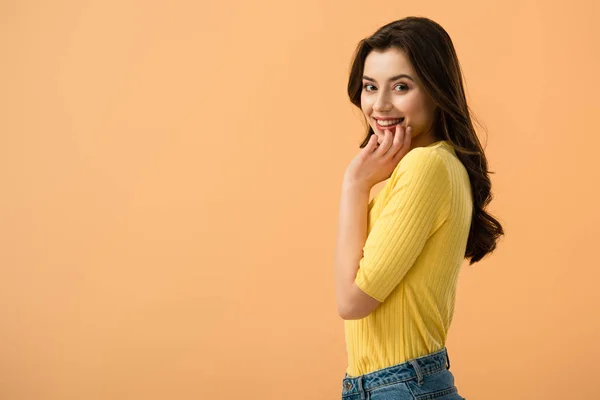 Fröhliche junge Frau lächelt, während sie isoliert auf orange steht — Stockfoto