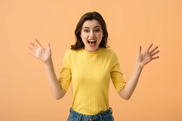Schockierte junge Frau schreit, während sie isoliert auf orange steht — Stockfoto