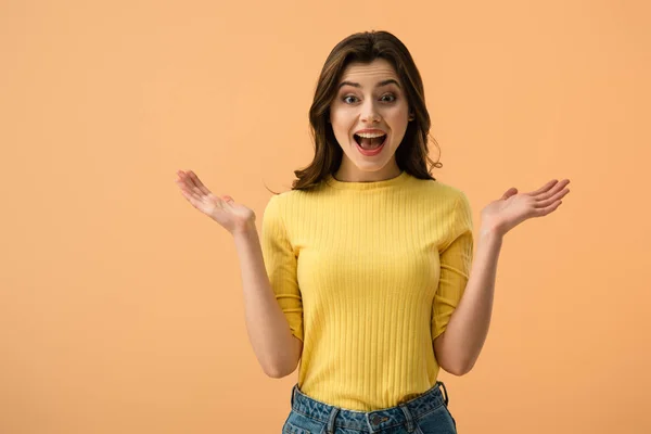 Mujer morena sorprendida haciendo gestos mientras está de pie aislado en naranja — Stock Photo