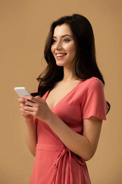 Happy brunette girl holding smartphone isolated on brown — Stock Photo