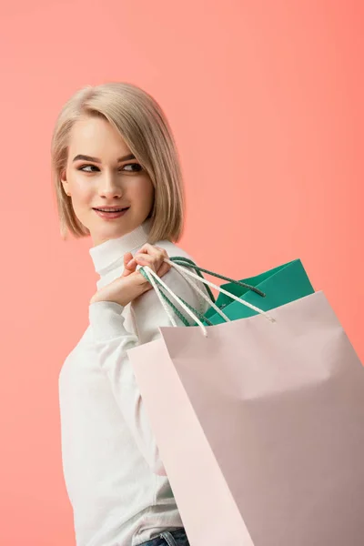 Joyeuse jeune femme blonde tenant des sacs à provisions isolés sur rose — Photo de stock