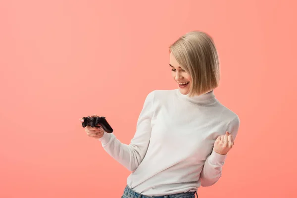 Cheerful blonde girl holding joystick and gesturing isolated on pink — Stock Photo