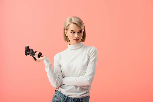 Upset blonde woman holding joystick while standing isolated on pink — Stock Photo