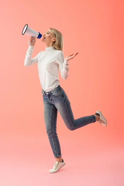 Fröhliche blonde Frau spricht im Megafon auf rosa Hintergrund — Stockfoto