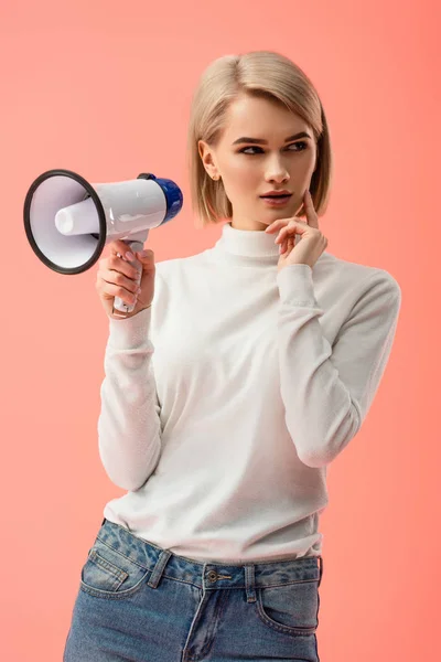 Donna bionda pensierosa che tiene il megafono isolato sul rosa — Foto stock