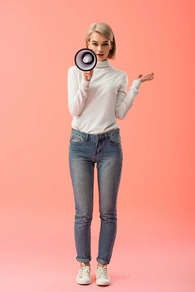 Attractive blonde woman speaking in megaphone on pink background — Stock Photo