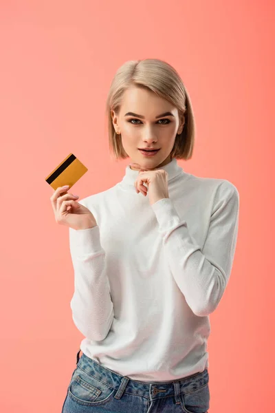 Весела блондинка тримає кредитну картку ізольовано на рожевому — стокове фото