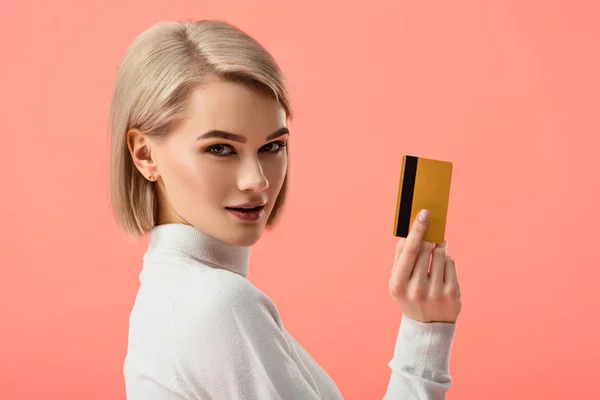 Приваблива блондинка тримає кредитну картку ізольовано на рожевому — стокове фото