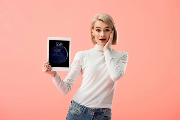 Überrascht blonde Frau hält digitales Tablet mit Sperrbildschirm isoliert auf rosa — Stockfoto