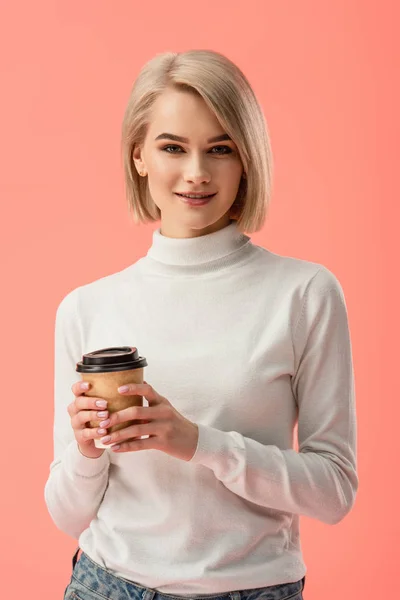 Приваблива блондинка тримає паперову чашку з напоєм ізольовано на рожевому — стокове фото