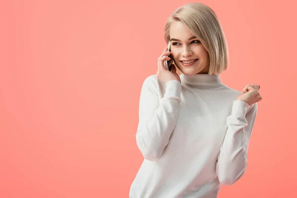 Mujer rubia bonita feliz hablando en el teléfono inteligente aislado en rosa - foto de stock