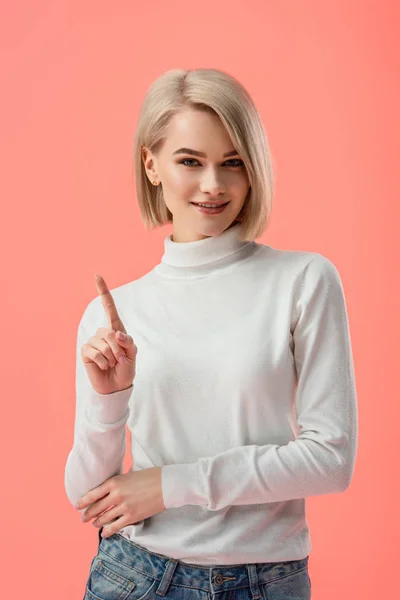 Attraktive blonde Mädchen steht und zeigt mit dem Finger isoliert auf rosa — Stockfoto