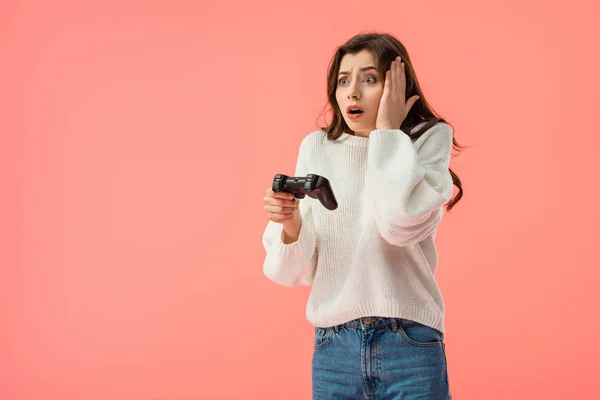 Schockiertes Mädchen hält Steuerknüppel, während es isoliert auf rosa steht — Stockfoto