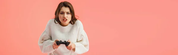 Tiro panorâmico de menina morena segurando joystick enquanto joga isolado em rosa — Fotografia de Stock