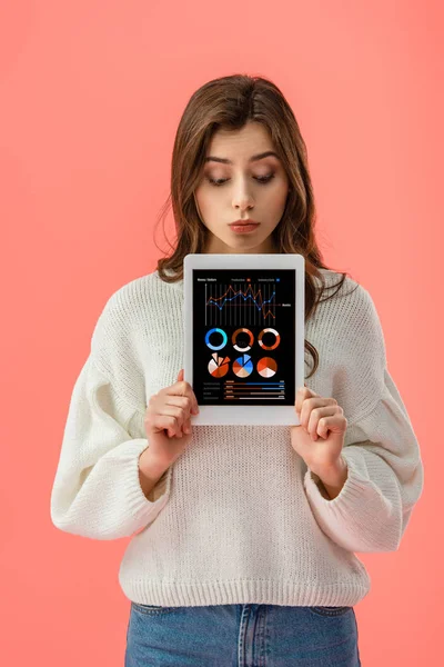 Surprised young woman holding digital tablet with charts and graphs on screen isolated on pink — Stock Photo