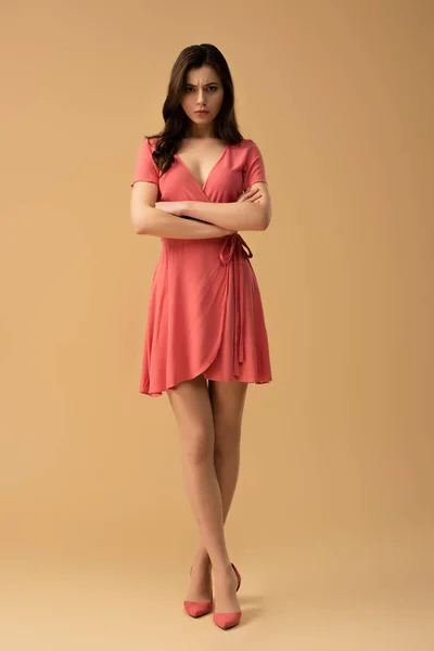 Attraente donna in piedi con braccia incrociate e gambe incrociate su sfondo marrone — Foto stock