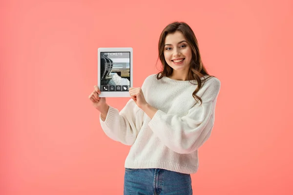 Sorrindo jovem segurando tablet digital com ingressos aplicativo na tela isolado em rosa — Fotografia de Stock