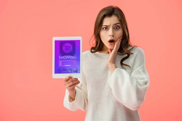 Sorprendió a mujer joven sosteniendo tableta digital con aplicación de compras en la pantalla aislada en rosa - foto de stock