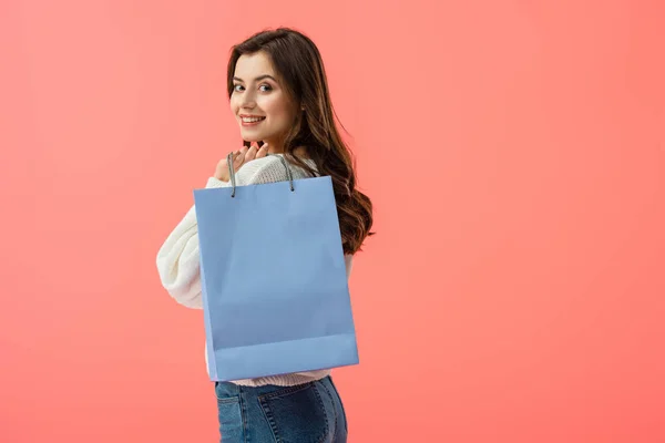 Smiling and attractive young woman holding shopping bag isolated on pink — Stock Photo