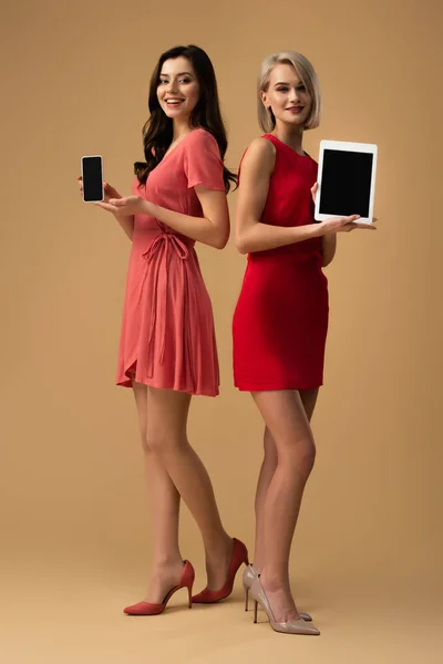 Frauen in roten Kleidern halten Smartphone und digitales Tablet mit Kopierplatz in der Hand — Stockfoto