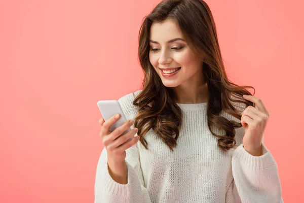 Lächelnde und attraktive Frau im weißen Pullover, Smartphone isoliert auf rosa — Stockfoto