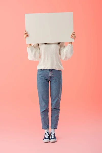 Visão de comprimento total da mulher em camisola branca e jeans segurando placa vazia com espaço de cópia — Fotografia de Stock