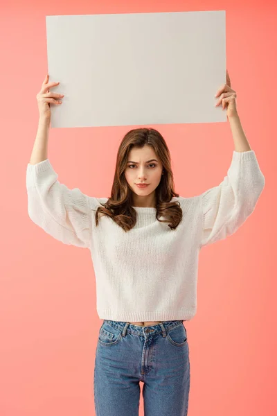 Sad woman in white sweater holding empty board with copy space isolated on pink — Stock Photo