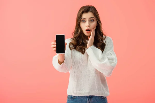 Shocked woman in white sweater holding smartphone with copy space isolated on pink — Stock Photo