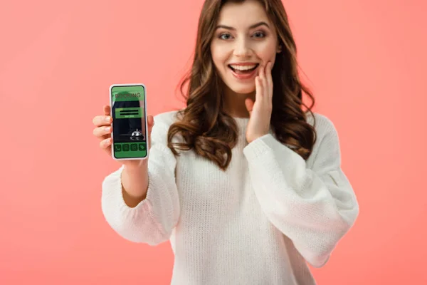 Selektiver Fokus der Frau im weißen Pullover, Smartphone mit Buchungs-App auf dem Bildschirm isoliert auf rosa — Stockfoto
