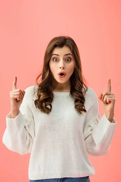 Surprised and beautiful woman in white sweater pointing with fingers isolated on pink — Stock Photo