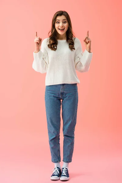 Visão de comprimento total de mulher sorridente e bonita em suéter branco apontando com os dedos — Fotografia de Stock
