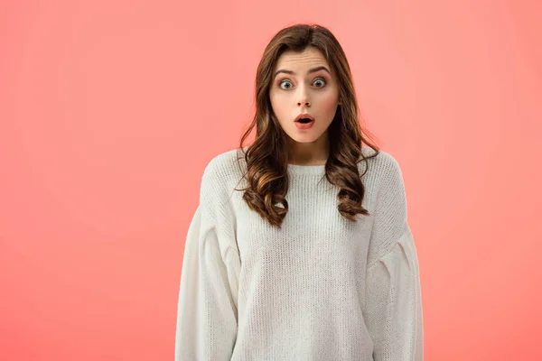 Surprised and attractive woman in white sweater looking at camera isolated on pink — Stock Photo