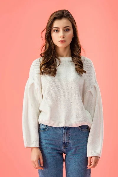 Brunette and attractive woman in white sweater looking at camera isolated on pink — Stock Photo
