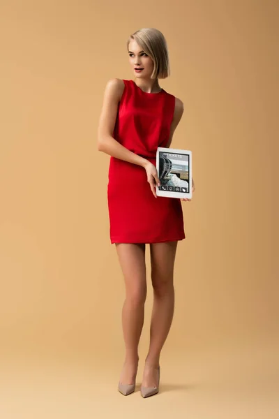 Full length view of woman in red dress holding digital tablet with tickets app on screen — Stock Photo