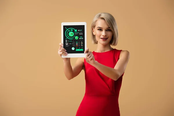 Schöne Frau in rotem Kleid mit digitalem Tablet mit Diagrammen und Diagrammen auf dem Bildschirm isoliert auf beige — Stockfoto