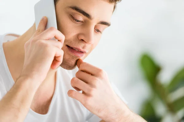 Portrait de bel homme en t-shirt parlant sur smartphone sur fond blanc — Photo de stock