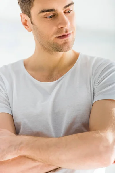 Portrait d'un bel homme en t-shirt à bras croisés sur fond blanc — Photo de stock