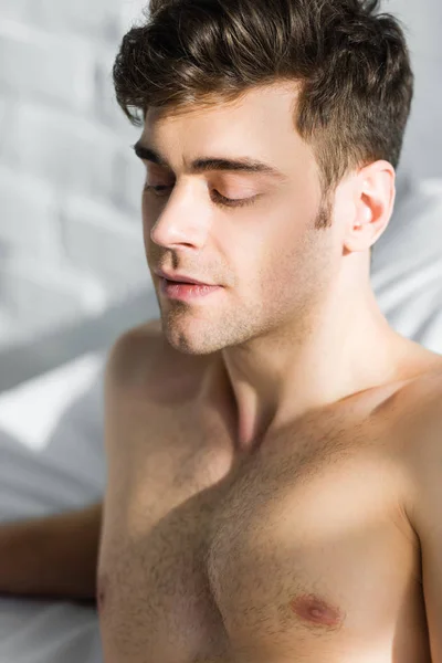 Portrait of handsome man with bare torso on bed — Stock Photo