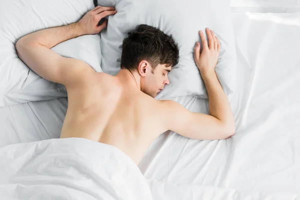 Top view of handsome man sleeping under white blanket on bad — Stock Photo