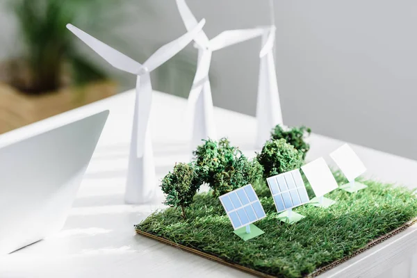 Tisch mit Bäumen, Windrädern und Solarmodellen auf Gras im Büro — Stockfoto