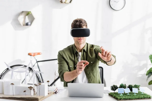 Architetto in realtà virtuale auricolare a tavola con laptop e modelli in ufficio — Foto stock