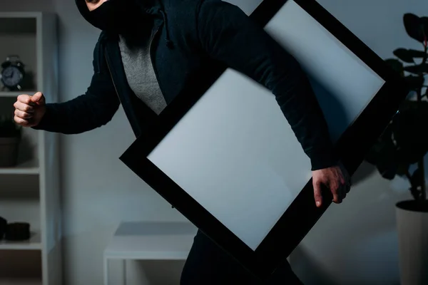 Partial view of thief stealing flat-screen tv with blank screen — Stock Photo