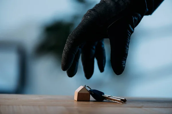 Partial view of thief in leather glove stealing keys — Stock Photo