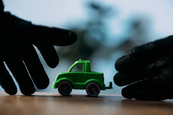 Vue partielle du voleur en gants noirs volant une voiture jouet — Photo de stock