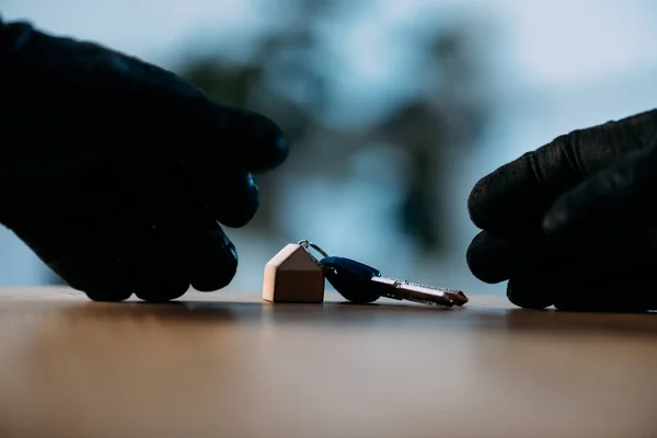 Partial view of thief in black gloves stealing keys — Stock Photo