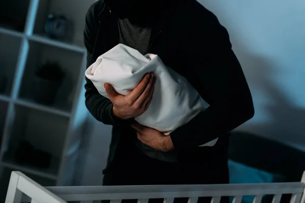 Обрезанный вид похитителя в черной одежде, держащего младенца — стоковое фото