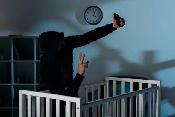 Kidnapper taking selfie near crib and showing peace sign — Stock Photo