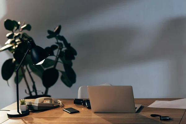 Ordinateur portable, smartphone, téléphone et pistolet sur la table dans le bureau — Photo de stock