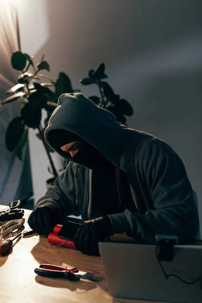 Concentrated terrorist in mask and gloves making bomb in room — Stock Photo