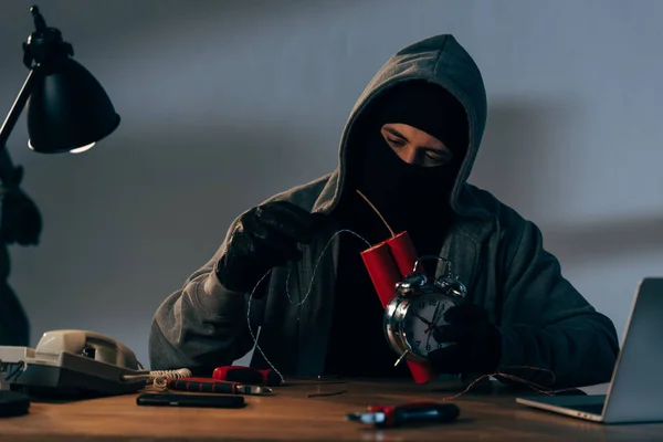 Concentrated terrorist in mask and gloves making bomb in room — Stock Photo